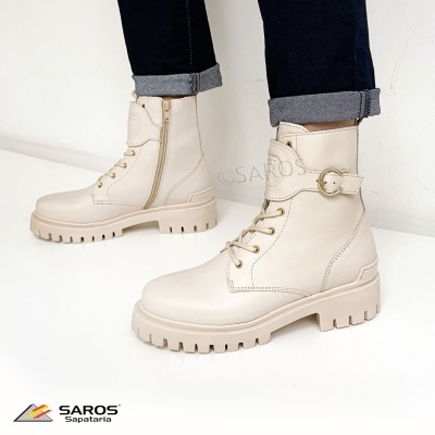 Botas de cano médio bege claro com atacadores e fivela, usadas com calças de ganga azul.