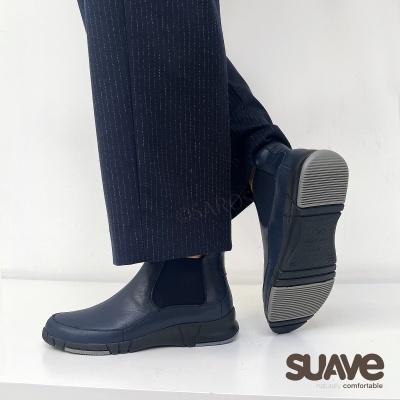 Botas Chelsea azuis com sola preta e detalhes cinzentos usadas com calças riscas pretas