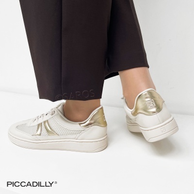 Tênis brancos com detalhes dourados metálicos e sola branca usados com calças castanho escuras