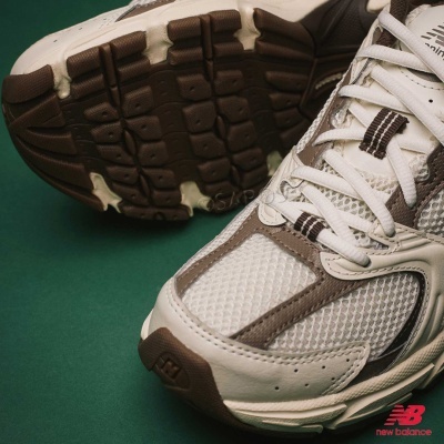 Ténis New Balance branco e castanho em fundo verde