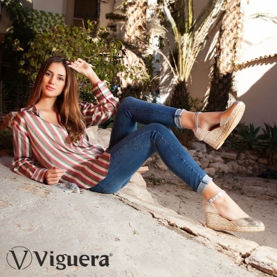 Mulher com camisa às riscas e calças de ganga reclinada ao ar livre com sapatos espadrilles