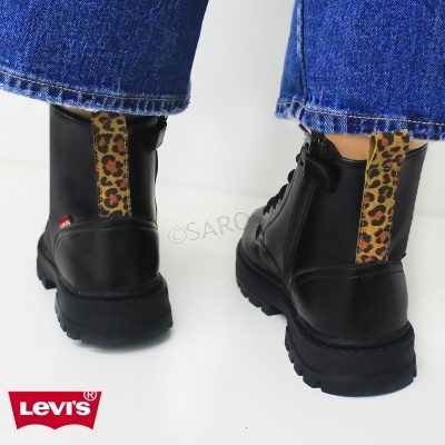 Botas pretas Levi's com padrão animal print e jeans azuis.