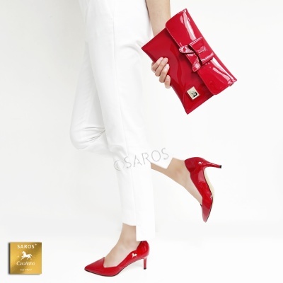 Mala de mão vermelha brilhante e sapatos vermelhos com calças brancas
