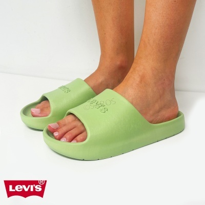 Chinelos verdes LEVIS em relevo usados por pés femininos sobre fundo branco