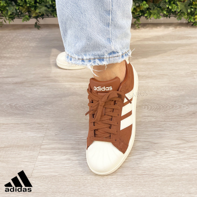 Sapatilhas Adidas castanhas com detalhes brancos usadas com calças de ganga