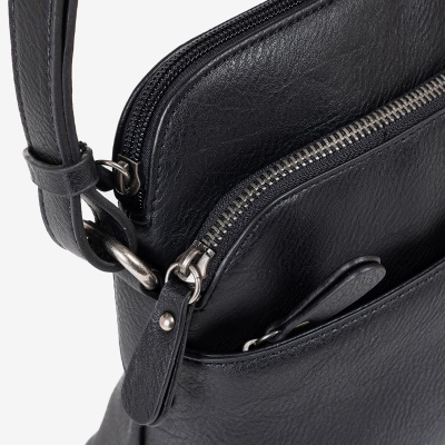 Close-up de mala preta em pele com fechos zip e alça ajustável.