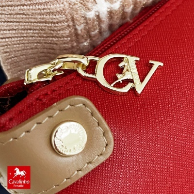 Fecho de zíper de mala vermelha com pingente dourado e puxador bege em pele sintética.