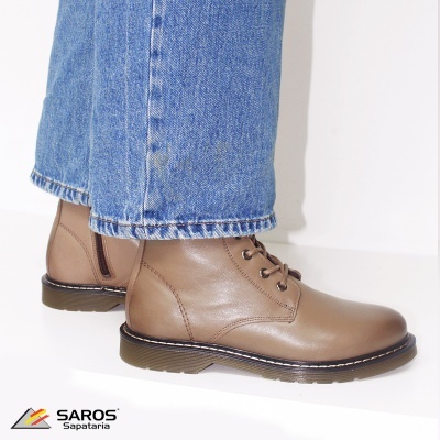 Botas castanhas em pele com sola preta usadas com calças de ganga azuis.