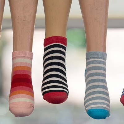 Três pares de meias curtas com padrões de riscas em várias cores em manequins.