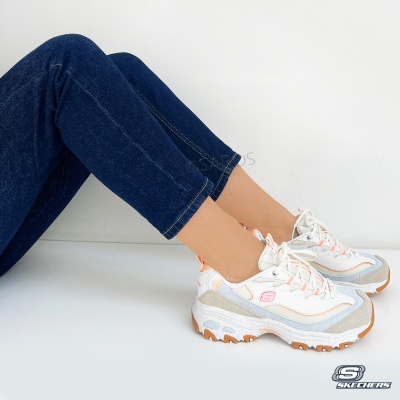 Ténis Skechers brancos com detalhes cinzento e laranja usados com calças de ganga