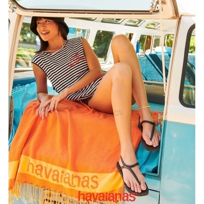Mulher numa carrinha vintage com roupa e toalha havaianas