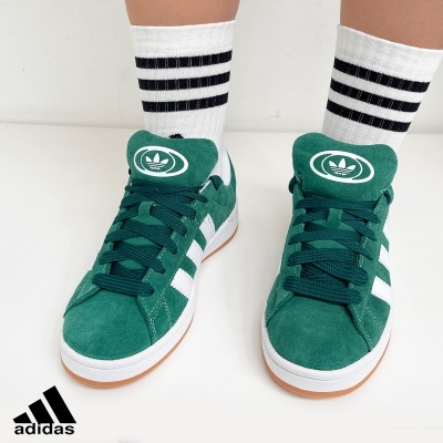 Ténis verdes Adidas com três riscas brancas e meias brancas às riscas pretas
