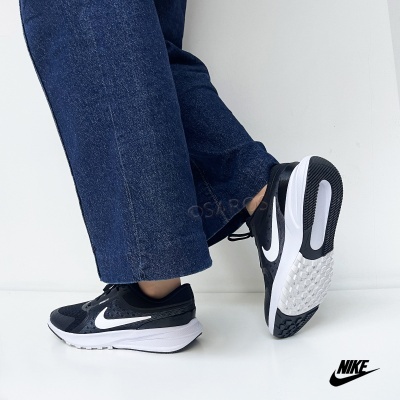 Ténis Nike pretos com sola branca usados com calças de ganga azuis