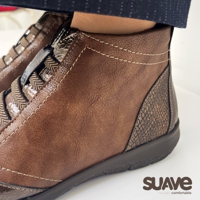 Sapatos castanhos com detalhes em preto metálico e sola preta num fundo branco