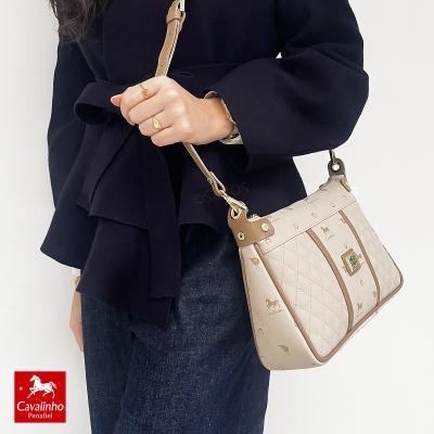 Mala de ombro Cavalinho bege e castanho claro com padrão de cavalos sobre casaco azul escuro