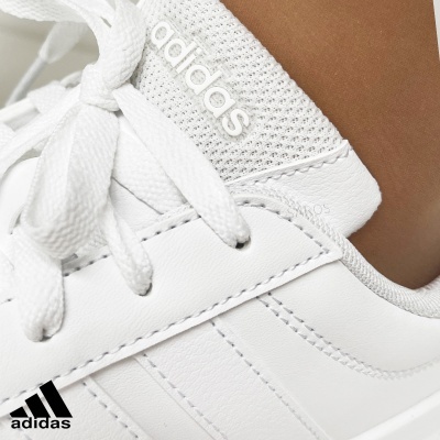 Sapatilha branca Adidas com logo em relevo e atacadores brancos