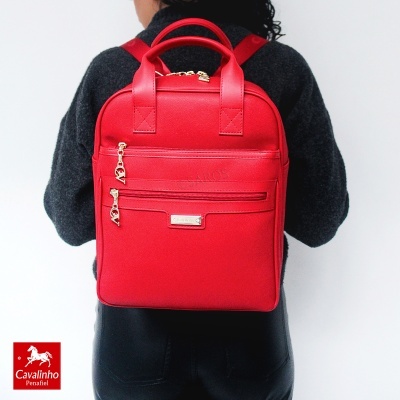 Mochila vermelha Cavalinho Penafiel com fechos dourados usada numa pessoa de costas