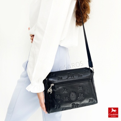 Bolsa tiracolo preta com relevos de borboletas e símbolos usada por mulher