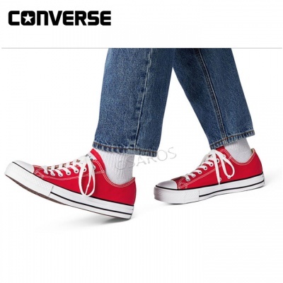 Ténis Converse vermelhos com atacadores brancos usados com meias brancas e calças de ganga azuis