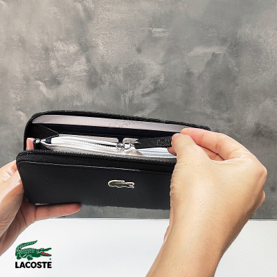 Carteira preta Lacoste com logótipo de crocodilo e fecho de correr aberta na mão
