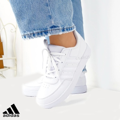 Ténis Adidas brancos com riscas laterais e jeans azuis claros