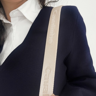 Alça bege com texto CÉLINE PARIS sobre casaco azul e camisa branca