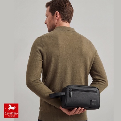 Homem de costas com camisola castanha a segurar necessaire preta