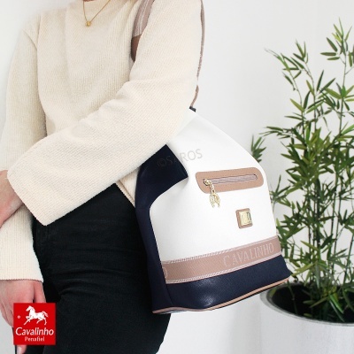 Mala de senhora branca, preta e bege com bolso frontal e fecho dourado e a marca CAVALINHO na faixa