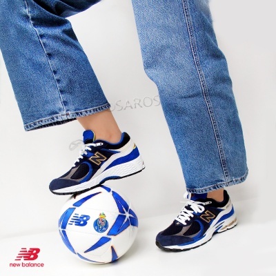 Ténis desportivos azuis New Balance e bola de futebol branca e azul com logótipos.