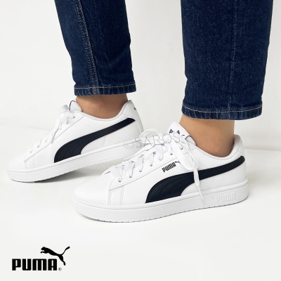 Ténis Puma brancos com detalhes pretos usados com calças de ganga azuis