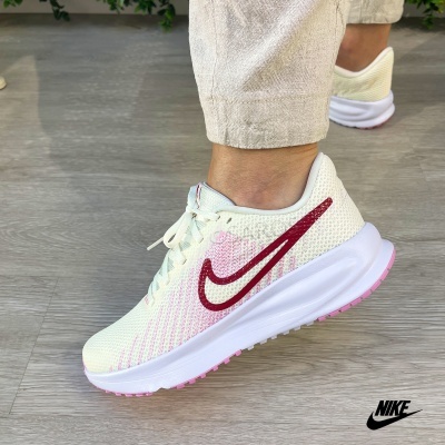 Ténis Nike brancos com detalhes rosa e vermelho num pé
