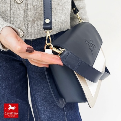 Mala de ombro azul escura com detalhes em bege e branco e alça ajustável