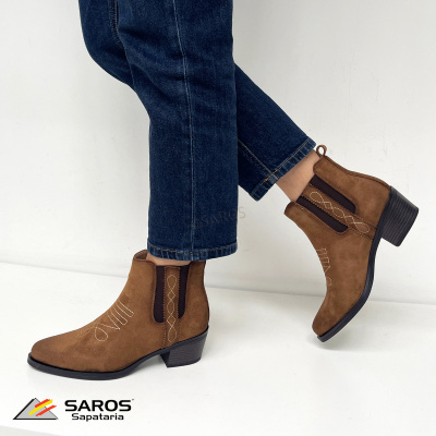 Botas castanho claro estilo western com bordados e salto grosso pretos usadas com jeans