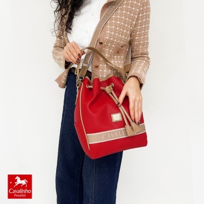 Saco vermelho Cavalinho com detalhes castanhos, usado por modelo com camisa branca e casaco castanho
