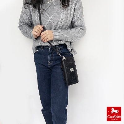 Mulher com camisola cinzenta, jeans azul escuro e mala preta de couro