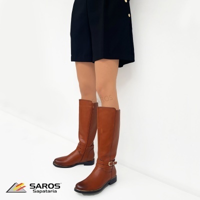 Bota castanha de pele com fecho lateral e fivela dourada usada com calções pretos