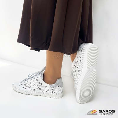Tênis brancos com padrão floral e detalhes prateados usados com saia castanha