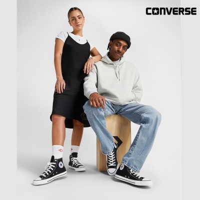 Homem e mulher com roupas casuais e ténis Converse pretos posando em estúdio branco