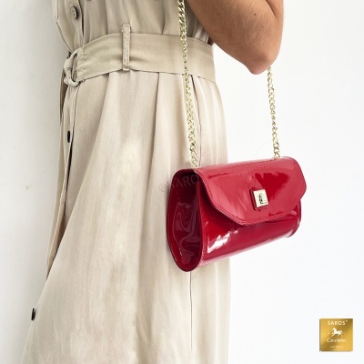 Mala vermelha em verniz com alça dourada em corrente e vestido bege claro