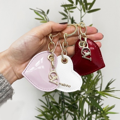 Chaveiros de coração em verniz rosa, bordô e pele branca com argolas douradas e letras pendentes.