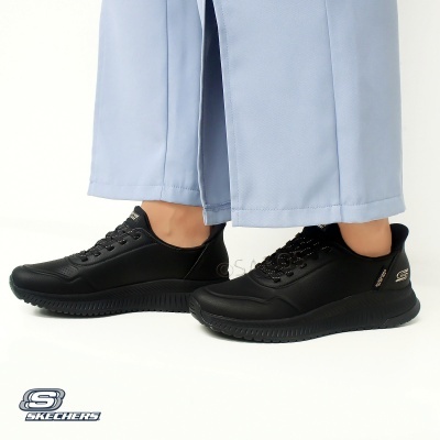 Ténis pretos Skechers com sola preta e calças azuis