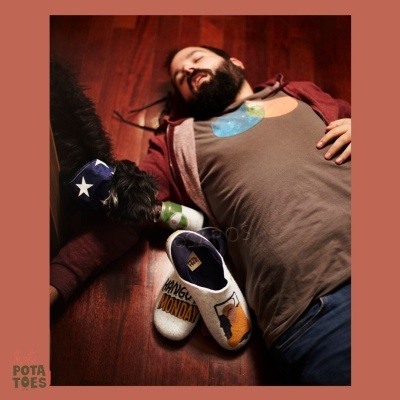 Chinelos de tecido com texto ao lado de homem e cão no chão de madeira