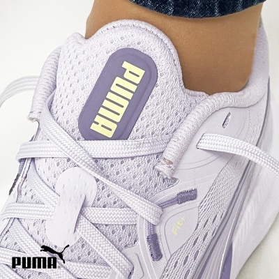 Ténis lilás claro PUMA em malha respirável com atacadores brancos e logo PUMA amarelo.