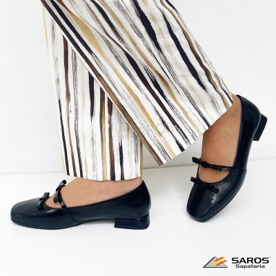 Sapatos pretos baixos com laços combinados com calças riscas castanho e bege