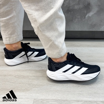 Ténis Adidas preto e branco com três riscas e sola espessa usados em interior