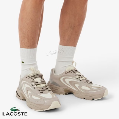 Ténis desportivos Lacoste bege e creme com meias brancas e logo verde.