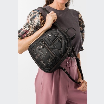Mochila preta acolchoada com inscrições e fecho frontal usada no ombro