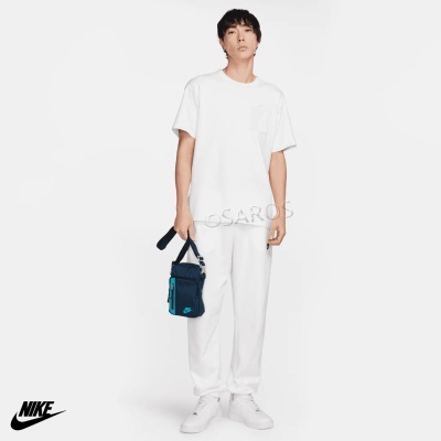 Homem com roupa desportiva branca e bolsa azul em fundo branco com logo Nike
