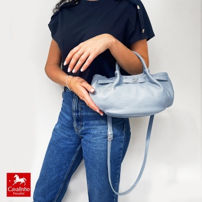 Bolsa azul em pele com alças e logótipo Cavalinho, mulher com t-shirt preta e jeans azuis