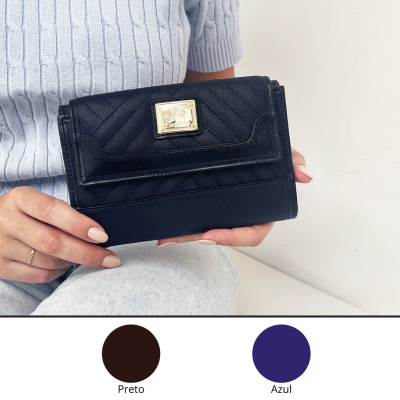 Carteira preta em pele sintética com fecho dourado segurada por pessoa